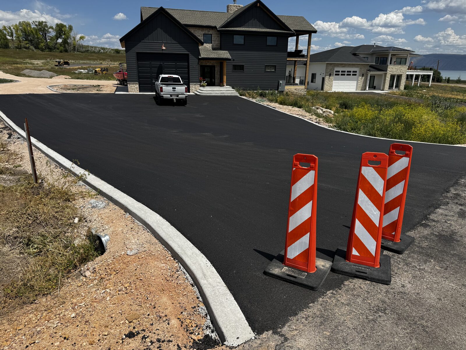 Freshly paved asphalt driveway at a Bear Lake cabin with the lake in the background