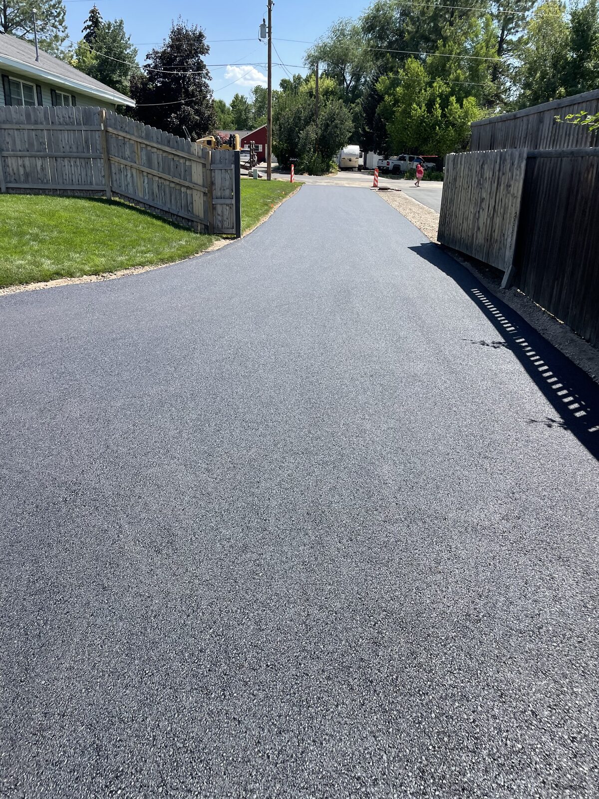 Newly paved asphalt driveway running between two fences on Utah's Wasatch Front
