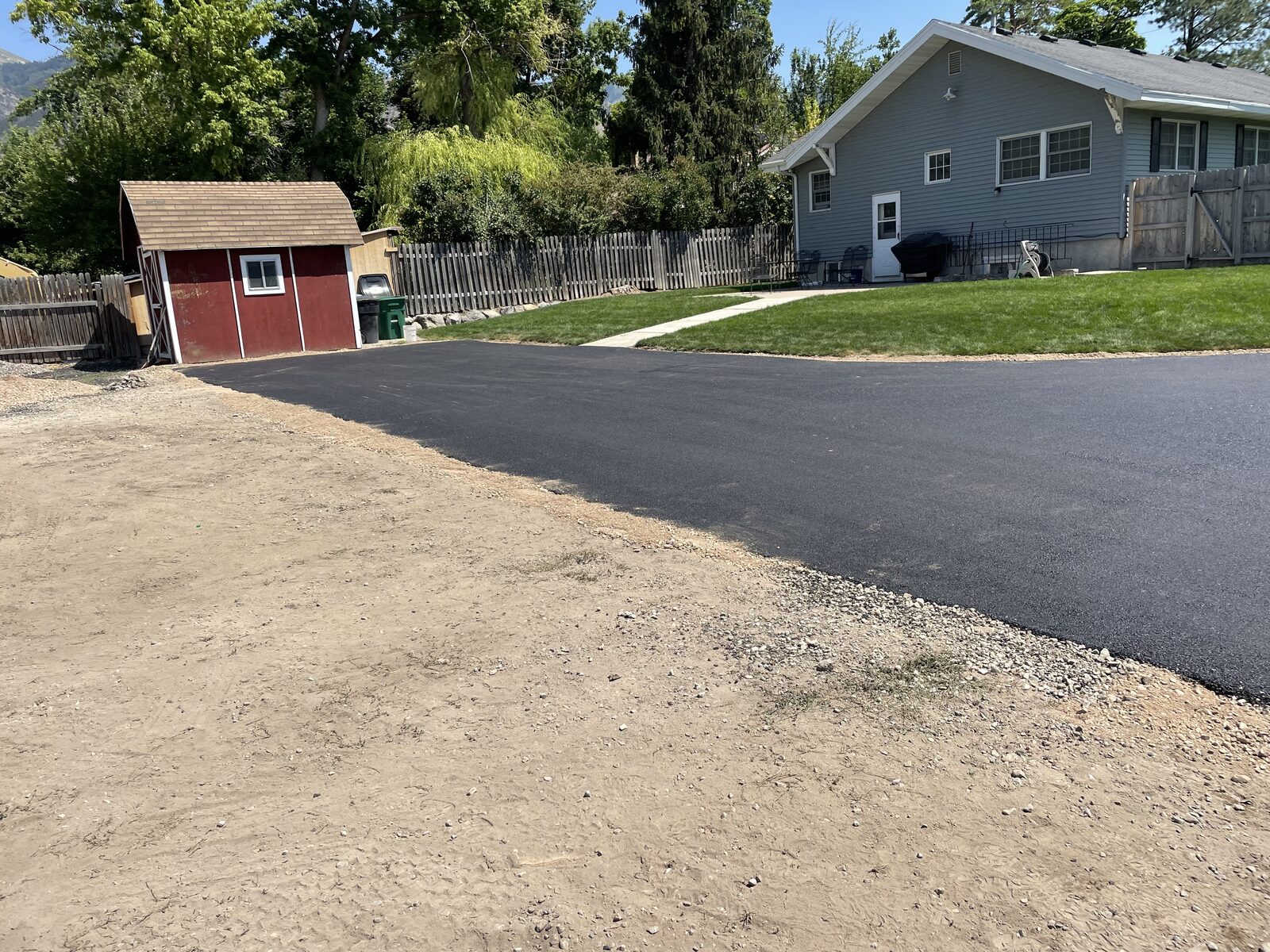 Freshly paved residential asphalt driveway beside a home on Utah's Wasatch Front with mountains in the background